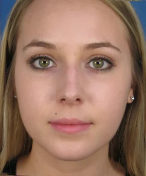 Portrait of a person with long blonde hair, green eyes, and a neutral expression, shown against a blue background.