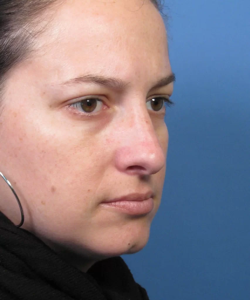 A person with dark hair and hoop earrings is looking off to the side against a blue background.