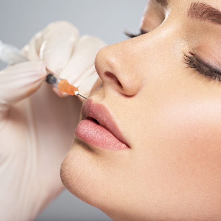 A person receives a lip injection with a syringe held by a gloved hand.