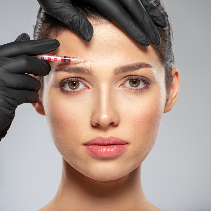 A person receives an injection in the forehead from a gloved hand.