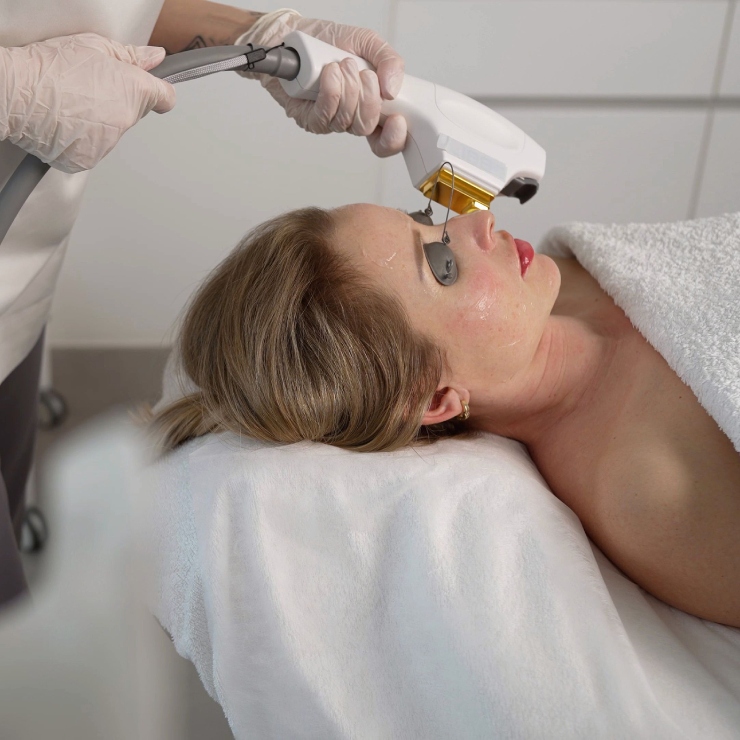 A person receives a laser facial treatment while lying on a spa bed.