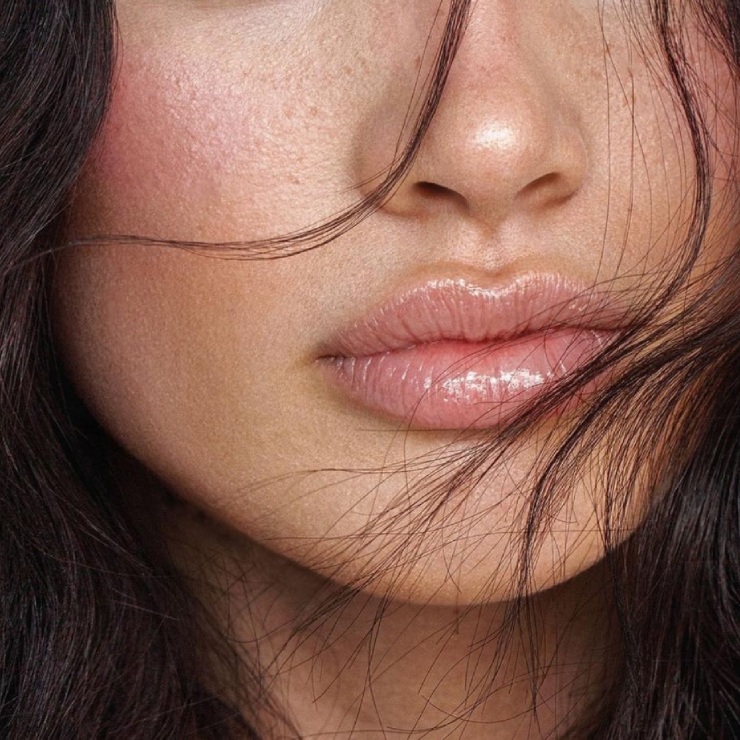 Close-up of a woman's lips and nose, with strands of dark hair partially covering her face.