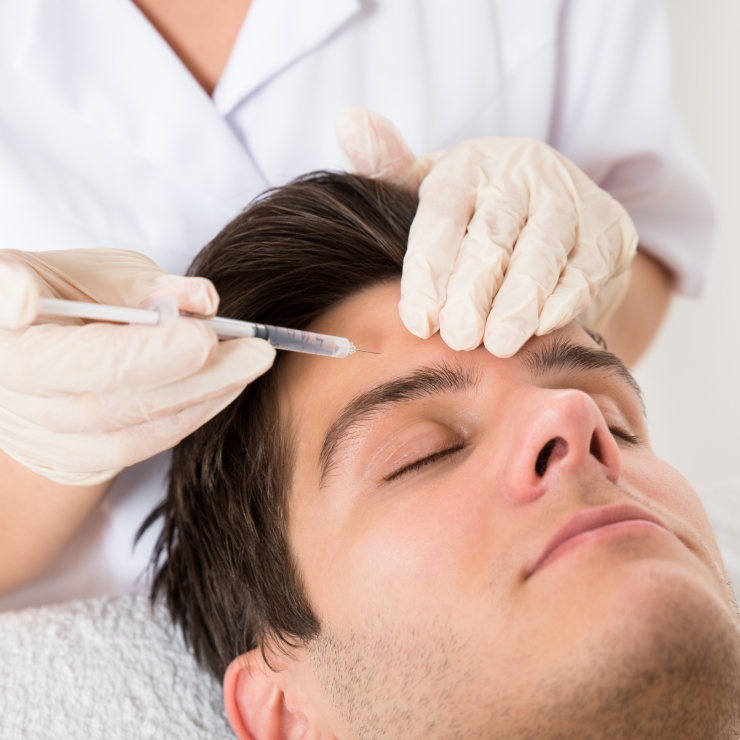 Person receiving an injection in the forehead from a professional wearing gloves.