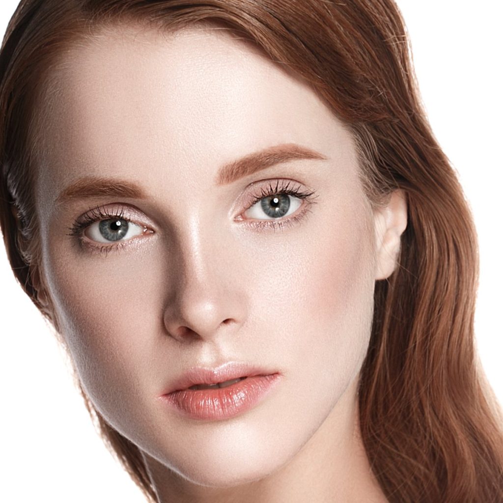 Close-up of a person with red hair and blue eyes against a white background.