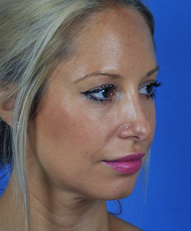 A woman with blonde hair and pink lipstick gazes to the side against a blue background.