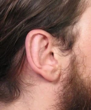 Close-up of a person's ear with long brown hair partially covering it.