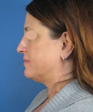 Profile view of a woman with long brown hair, wearing a gray sweater, against a blue background.