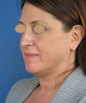 Profile of a woman with medium-length brown hair, wearing a gray sweater and small hoop earrings, set against a blue background.