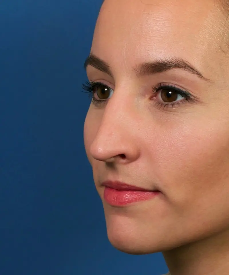 A person with light skin and brown eyes is shown in profile against a blue background.