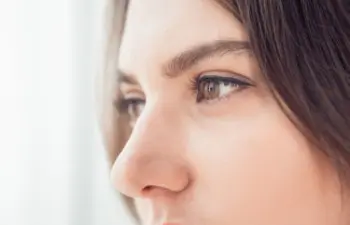 Close-up of a person's face in profile, focusing on their eyes and nose, with brown hair partially visible.