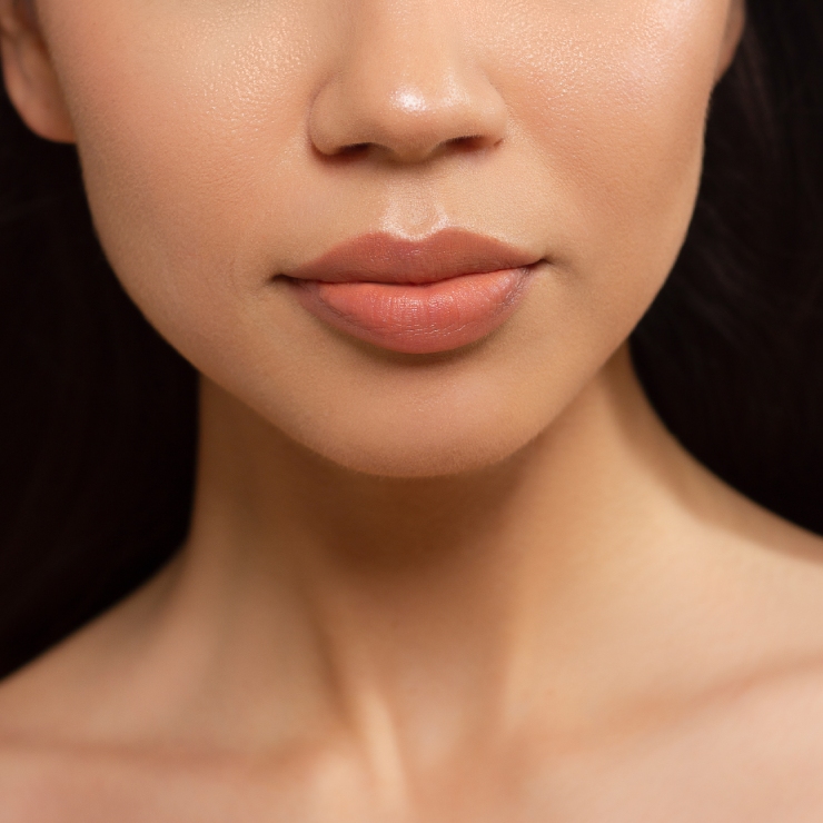 Close-up of a woman's lower face and neck, with smooth skin and neutral makeup tones.