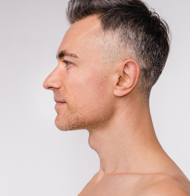 Profile view of a man with short hair, looking to the left against a plain background.