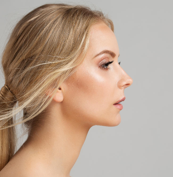 Profile view of a woman with blonde hair pulled back, looking to the right, against a neutral background.