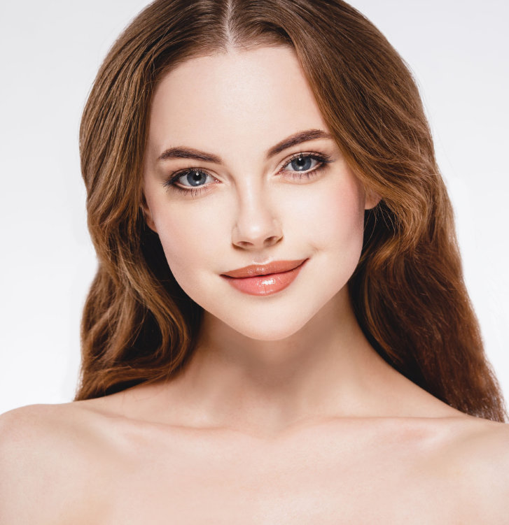 A woman with long brown hair smiles softly against a plain background.